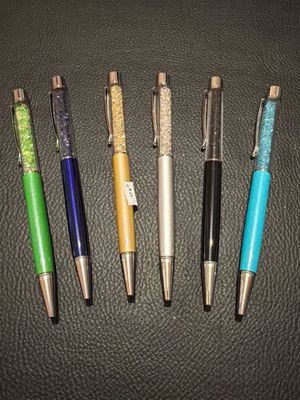 four different colored pens lined up on top of a black surface