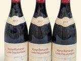 three bottles of wine are lined up on a white surface