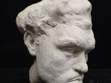 a white sculpture of a man ' s head on a black surface