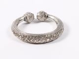 a close up of a silver bracelet on a white surface