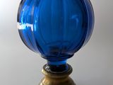 un vase en verre bleu avec un socle doré posé sur une table