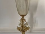 a glass goblet sitting on a table in front of a white wall