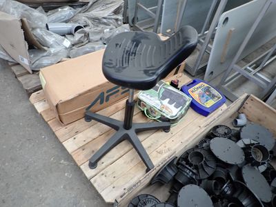 une chaise noire posée sur une palette, à côté d'un tas d'ordures