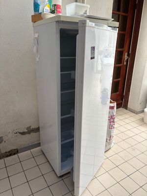 a white refrigerator in the corner of a room with tile flooring