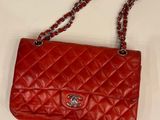 a red chanel bag with a chain strap on a white surface