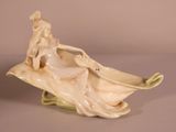 a figurine of a woman sitting on a leaf