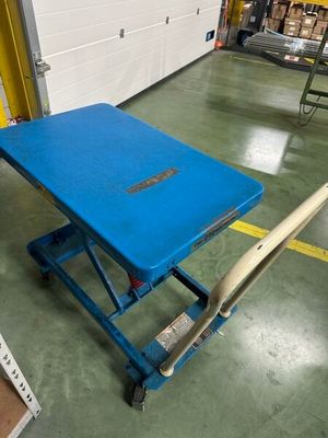 une table bleue sur laquelle repose une batte de baseball, dans un entrepôt