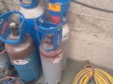 Plusieurs bouteilles de gaz propane et des tuyaux sont alignés contre un mur