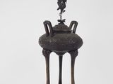 an old bronze vase with a bird on top of it