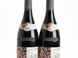 two bottles of wine sitting next to each other on a white surface