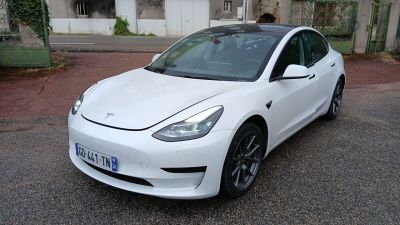 a white tesla car parked on the street in front of a building