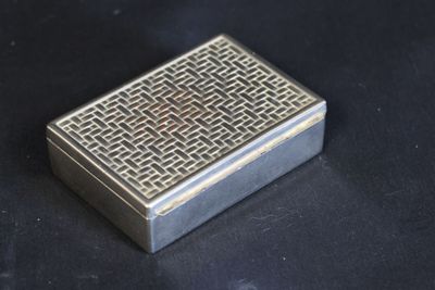 an old silver cigarette case sitting on top of a black table