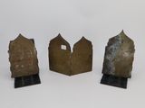 three bronze bookends of different shapes and sizes on a white surface