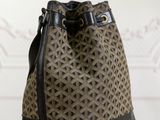 the brown and black bucket bag is sitting on a wooden table