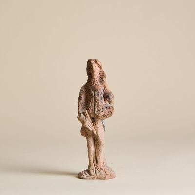 une vieille statue représentant un homme tenant un oiseau, posée sur une surface blanche