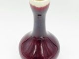 a red and white vase sitting on a white surface