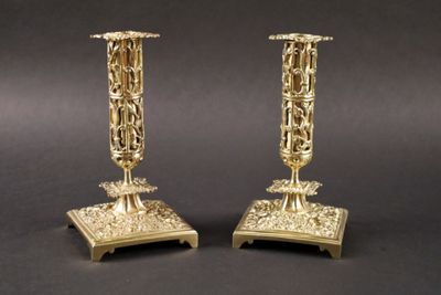 paire de bougeoirs anciens en laiton sur un socle, sur fond noir