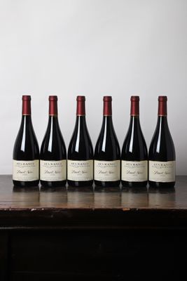 six bouteilles de vin rouge alignées sur une table en bois