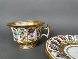 two cups and saucers with floral designs on them on a table
