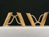 two gold earrings are sitting on top of a white cake