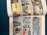 someone is reading a comic book on a table with a cup of coffee next to it