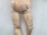 a wooden doll laying on the floor with a blanket on it ' s back