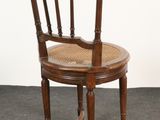 an image of a wooden chair with a wicker seat on a carpeted floor