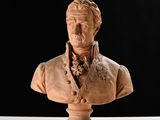 statue représentant le buste d'un homme sur un socle, sur fond noir