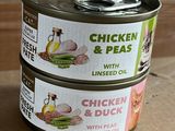 Deux boîtes de poulet aux petits pois à l'huile de lin sont posées sur une table