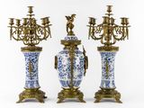 three blue and white vases and a candelabra on a stand