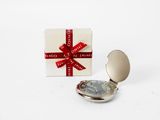 a small silver pocket watch with a red ribbon around it