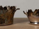 two silver vases sitting on a table next to each other