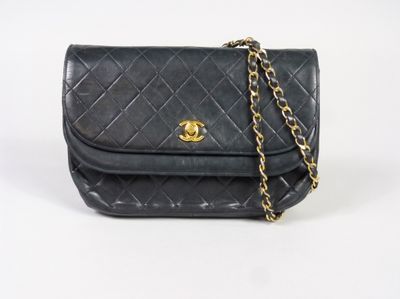 un sac Chanel noir muni d'une bandoulière en chaîne dorée
