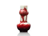 une photo d'un vase rouge et blanc posé sur une surface blanche