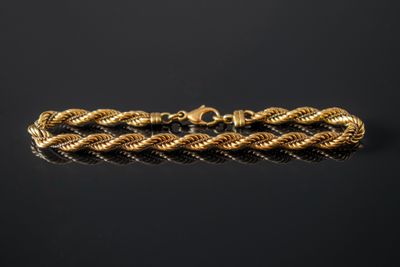 un bracelet en or avec un motif tressé sur fond noir