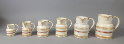 several white and brown vases are lined up against a gray background