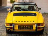 yellow porsche 911 carrol parked on cobblestone road in urban setting