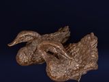 bronze sculpture of a duck on a branch on a blue background