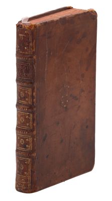 an old book with a brown cover sitting on top of a white surface