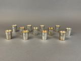 six silverplated cups with gold rims on a table