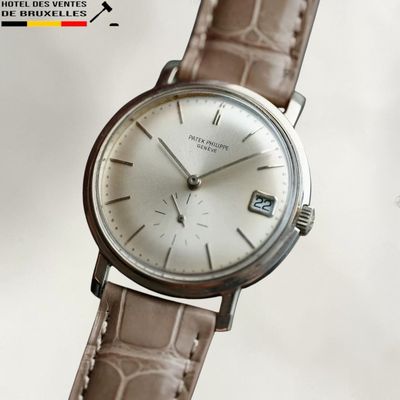 une montre argentée avec un bracelet marron sur fond blanc