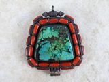 a close up of a red and green stone pendant on a white surface