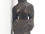 a wooden sculpture of a woman holding a bowl
