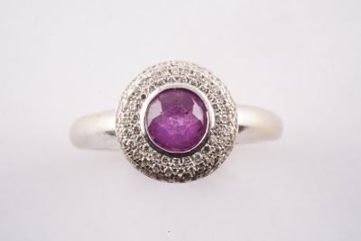 gros plan d'une bague avec une pierre violette entourée de diamants