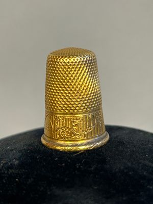 a close up of a gold thimble on a black surface