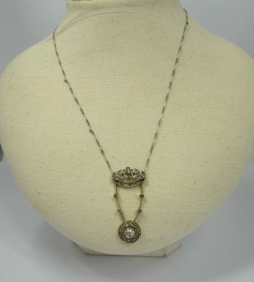 a white mannequin with a necklace and a crown on it