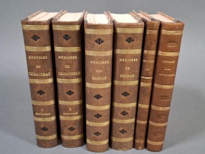 six vieux livres sont alignés sur une surface grise