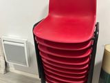 une pile de chaises en plastique rouges à côté d'une poubelle