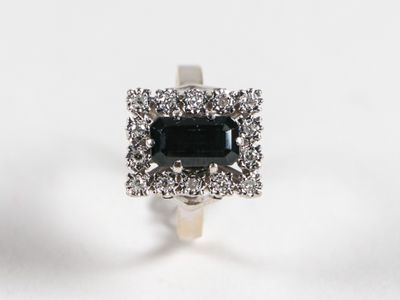 un gros plan d'une bague en diamant noir et blanc posée sur une surface blanche