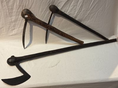 une paire d'outils de jardinage anciens et rouillés posés sur une surface blanche